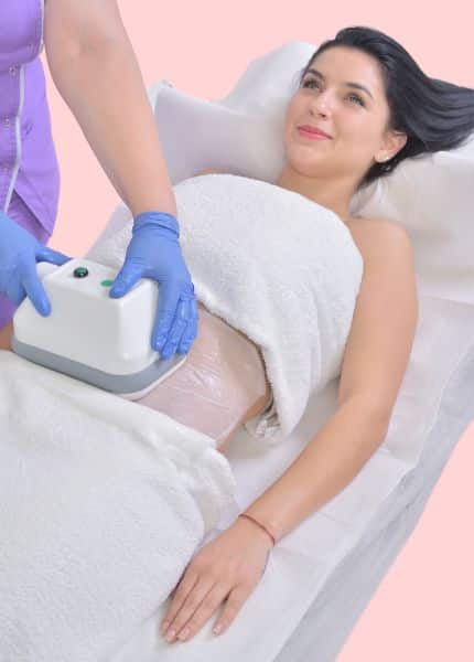25% weniger Fett mit Kryolipolyse Eine junge Frau liegt auf einer Liege. Auf ihrem Bauch befindet sich eine Folie über welche ein Kryolipolyse-Gerät geführt wird.
