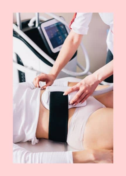 HI-EMT und RF Behandlungen für eine schlanke Linie Ein HI-RMT und RF-Gerät wird auf dem Bauch einer liegenden Frau, die einen weißen Slip und ein weißes Shirt trägt, befestigt.